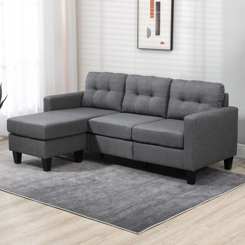 Gray sectional sofa in a living room setting with a rug and wall art.
