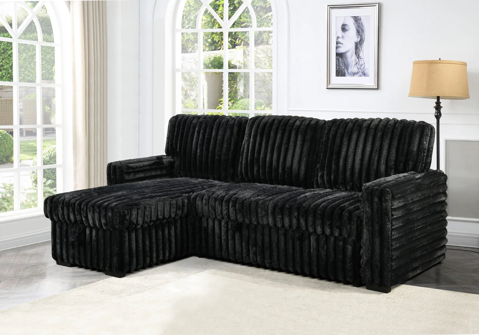 Black sectional sofa in a room with large windows and a lamp.