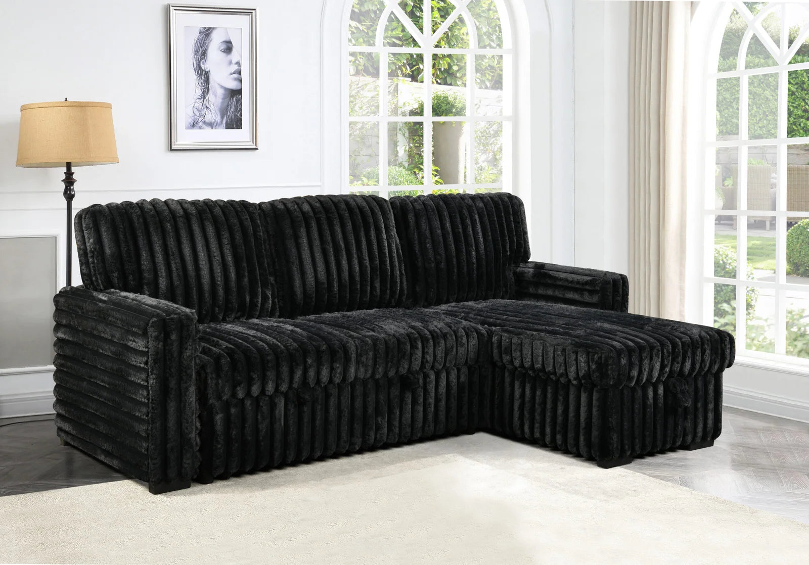 Black sectional sofa in a room with large windows and a lamp.