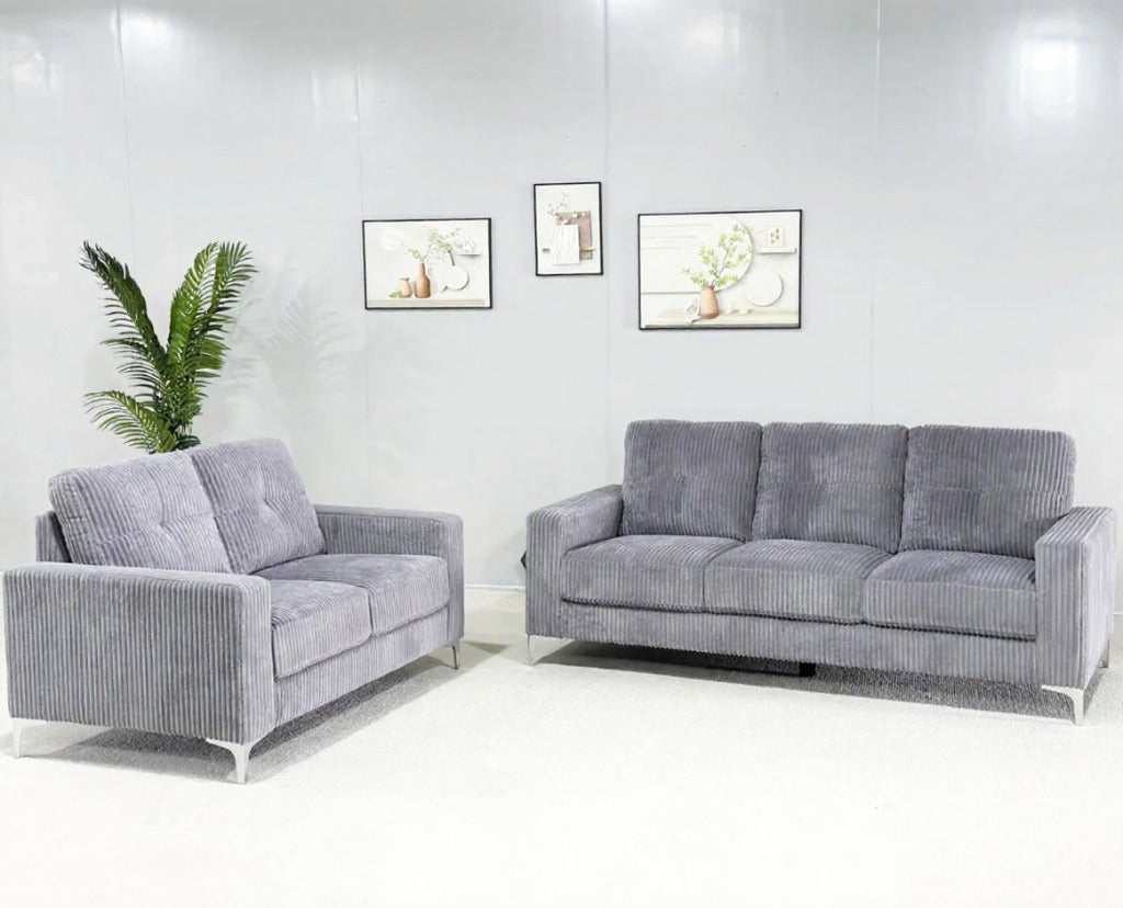 Gray sofa set in a room with white walls and a plant.
