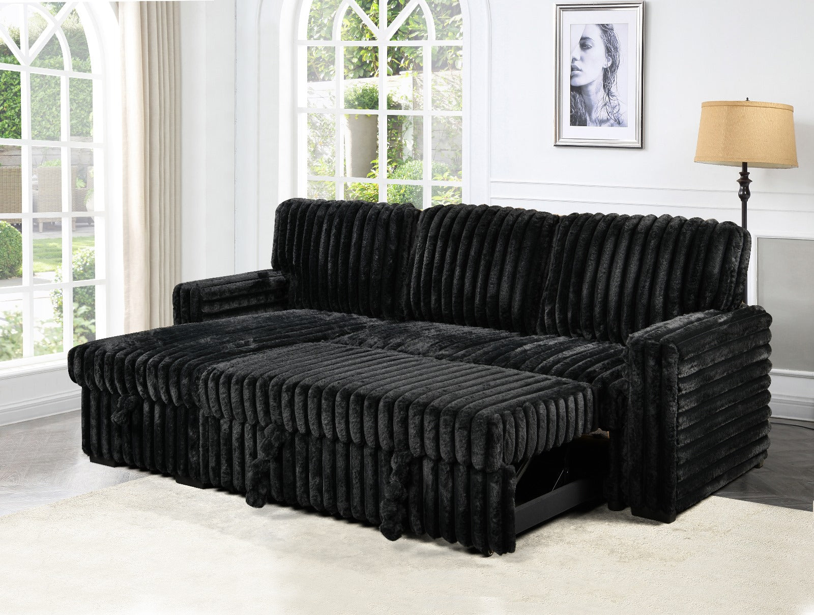 Black sectional sofa in a room with large windows and a lamp.