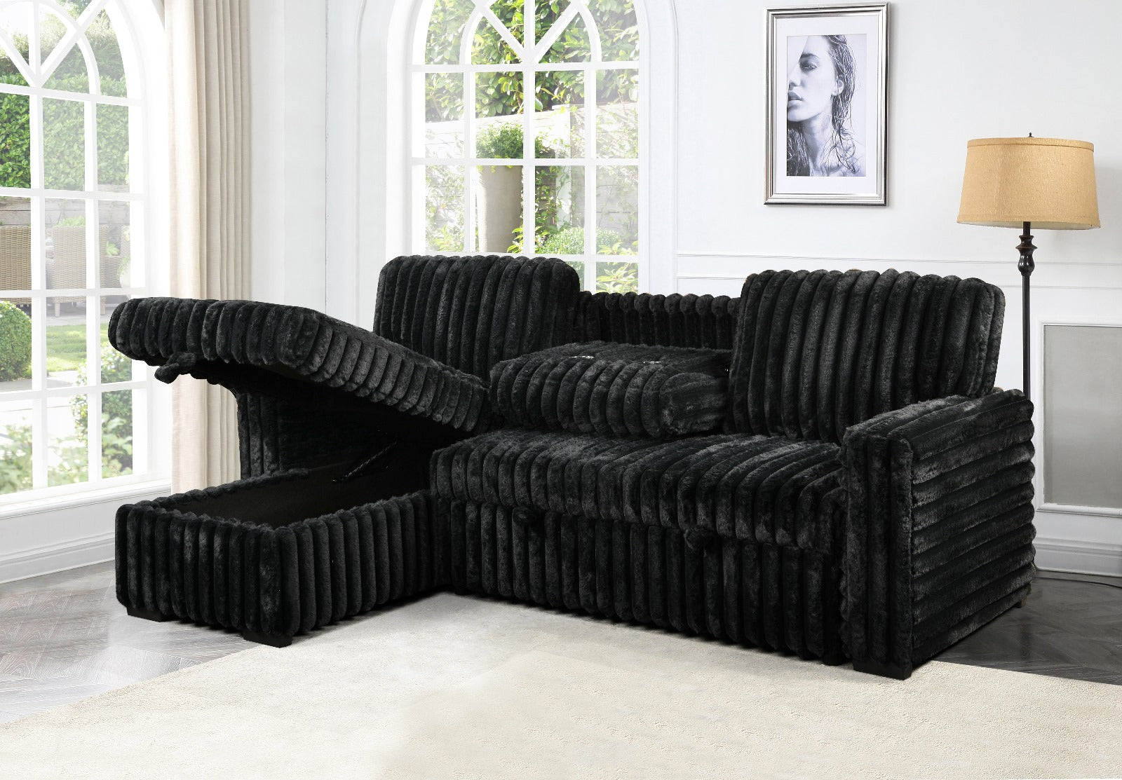 Black sectional sofa in a living room with large windows and a lamp.