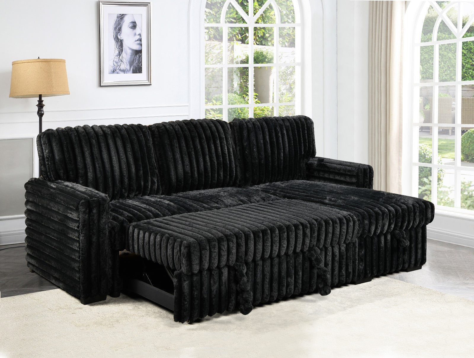 Black sectional sofa in a room with large windows and a lamp.