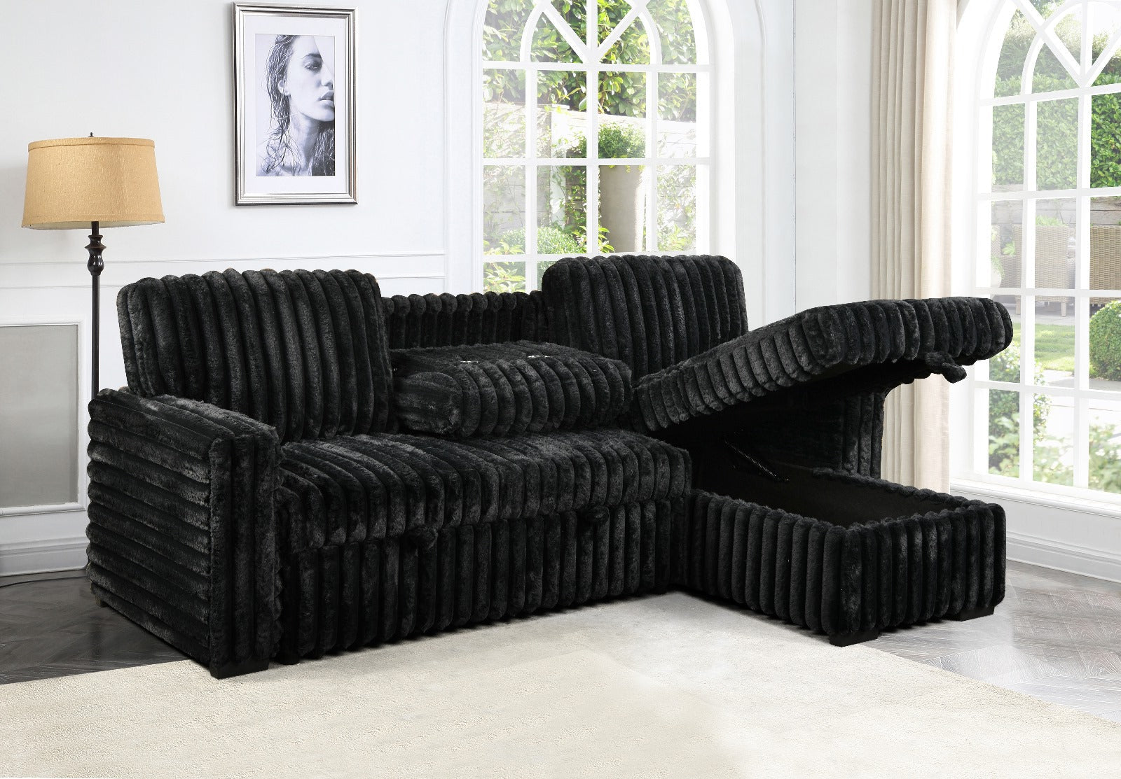 Black sectional sofa in a living room with large windows and a lamp.