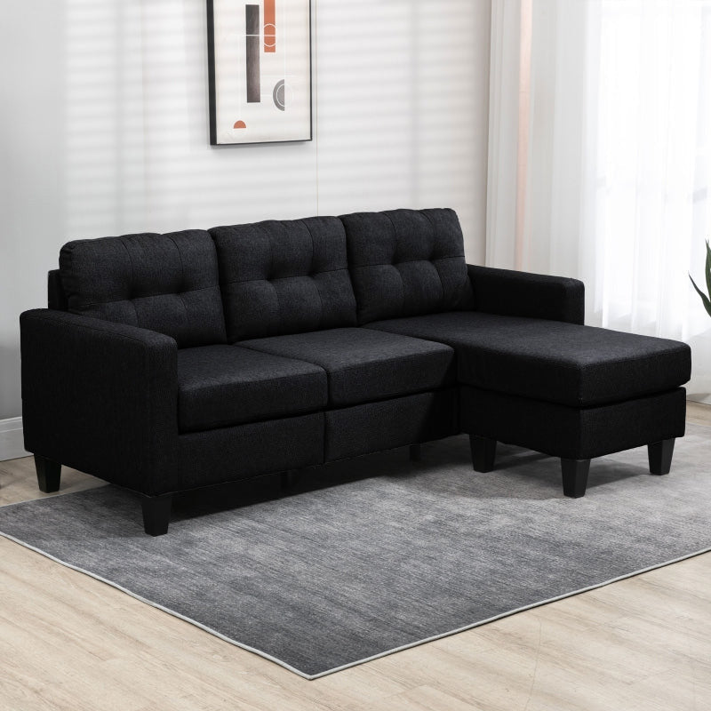 Black sectional sofa in a room with a gray rug and white walls.